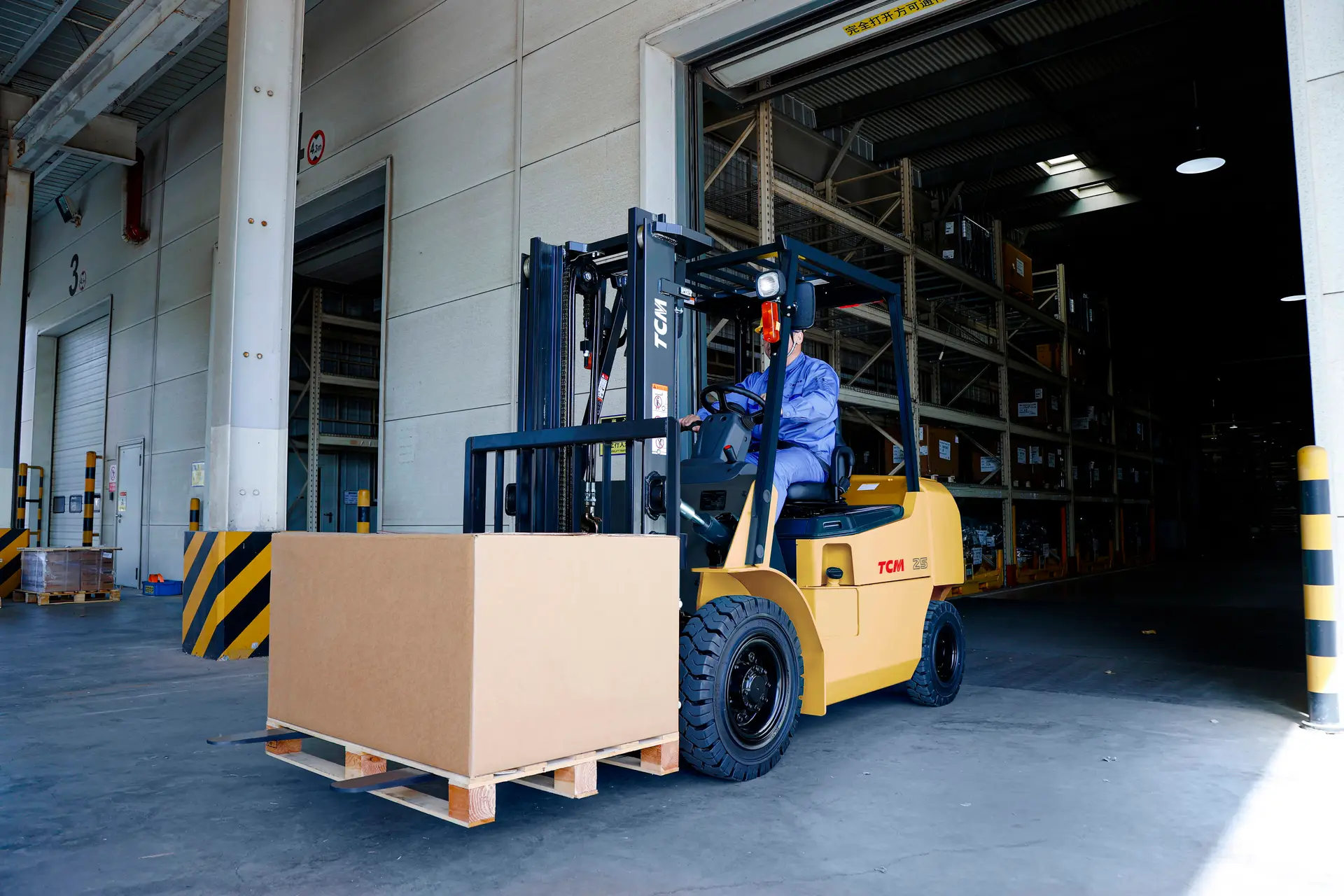 Operator driving a TCM Forklift from Criterion Equipment, moving a pallet at a warehouse loading dock to demonstrate reliable industrial performance